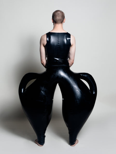 A person wearing black inflatable trousers shaped like a vase with handles at the waist with Tank top
