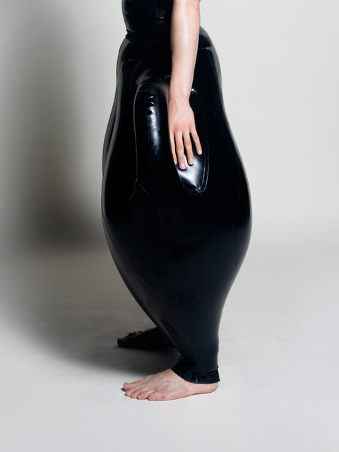 A person wearing black inflatable trousers shaped like a vase with handles at the waist with Tank top
