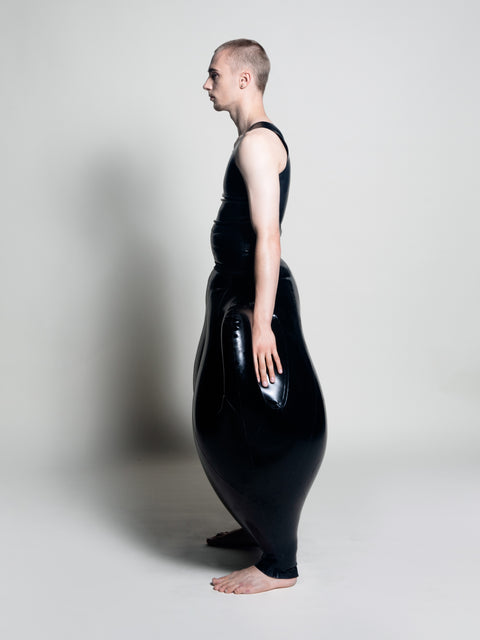A person wearing black inflatable trousers shaped like a vase with handles at the waist with Tank top