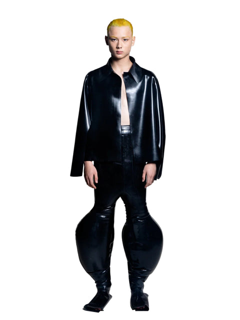 A person standing wearing black inflatable trousers with an alien-like silhouette, including extra-large legs.