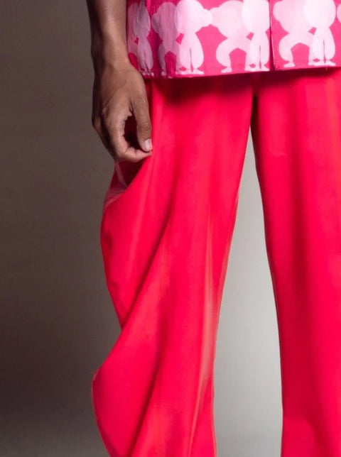 Person wearing a pink and white patterned shirt with bright pink pants on a white background