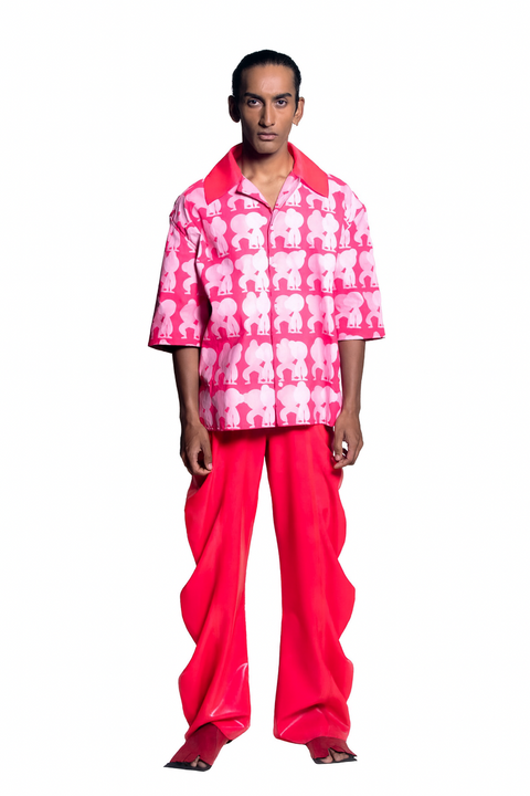 Person wearing a pink and white patterned shirt with bright pink pants on a white background