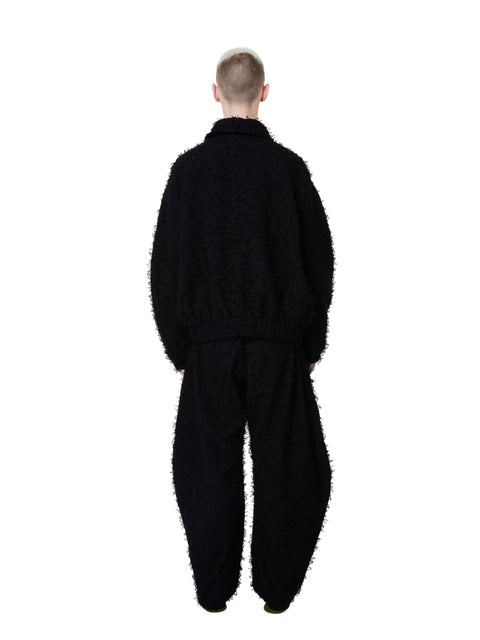 Person wearing a black textured outfit on a white background