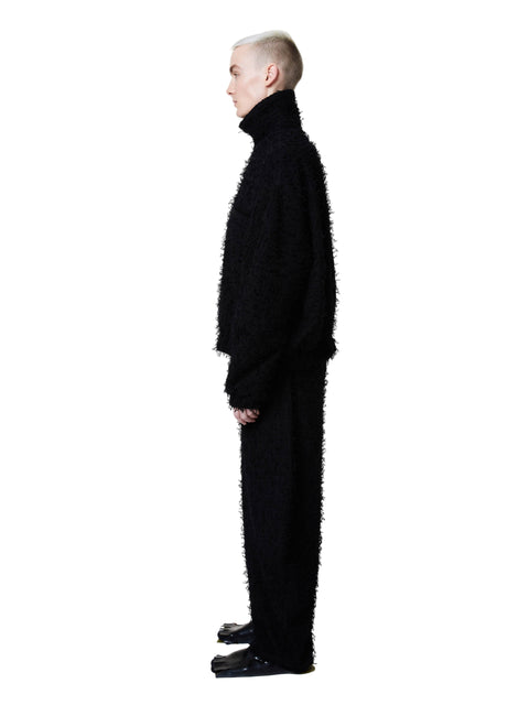 Person wearing a black textured outfit on a white background