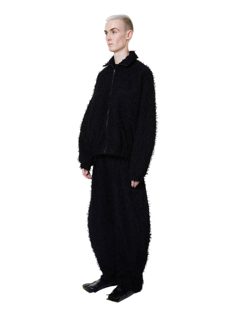 Person wearing a black textured outfit on a white background