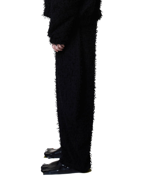 Black textured pants worn by a person on a white background