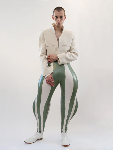 A model wearing white and olive striped inflatable trousers with a beige jacket, standing against a plain background.