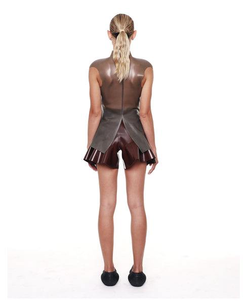 Woman wearing brown high waist flared shorts from HARRI with a unique sheer top and black slip-on shoes