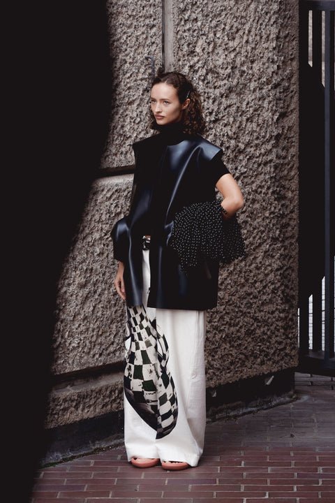 Black structured latex overshirt with wide-leg printed trousers from HARRI London SS26 MuseumWear, photographed by Rossella Damiani