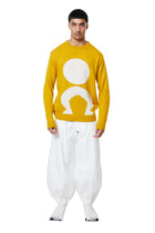Person wearing a yellow sweater with a white graphic design on a white background