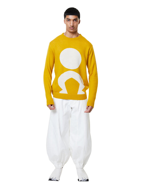 Person wearing a yellow sweater with a white graphic design on a white background