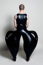 A person wearing black inflatable trousers shaped like a vase with handles at the waist with Tank top