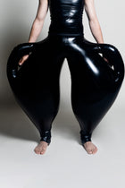 A person wearing black inflatable trousers shaped like a vase with handles at the waist with Tank top
