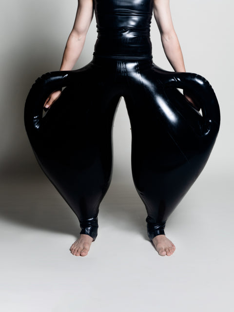 A person wearing black inflatable trousers shaped like a vase with handles at the waist with Tank top
