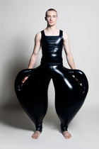 A person wearing black inflatable trousers shaped like a vase with handles at the waist with Tank top