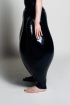 A person wearing black inflatable trousers shaped like a vase with handles at the waist with Tank top
