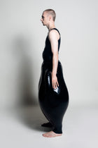 A person wearing black inflatable trousers shaped like a vase with handles at the waist with Tank top