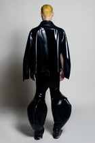 A person standing wearing black inflatable trousers with an alien-like silhouette, including extra-large legs and Cape