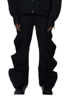 A person standing wearing deflated signature black denim trousers with an oversized style.
