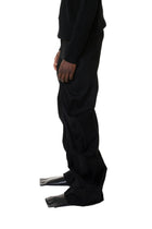 Person wearing black denim pants on a white background