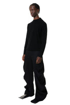 Person wearing a black denim outfit on a white background