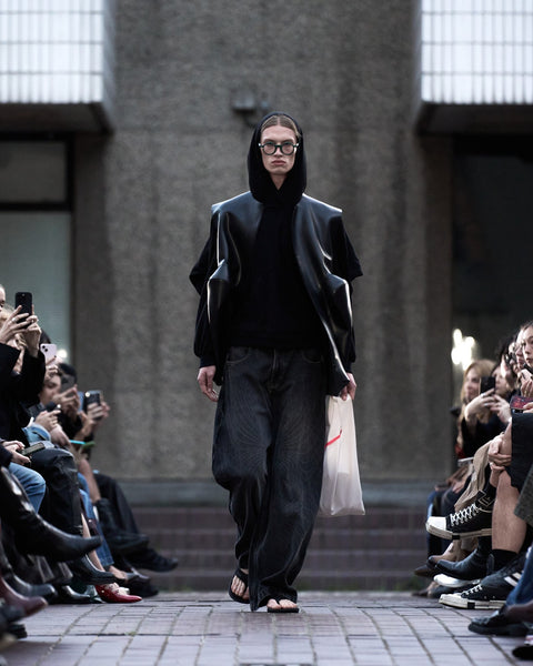 HARRI Black hoodie layered with a black coat, paired with printed black denim
