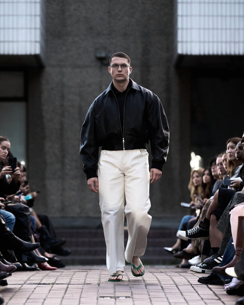 HARRI Classic black shirt layered under black leather jacket and paired with white leather trousers