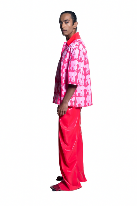 Person wearing a pink and white patterned shirt with bright pink pants on a white background
