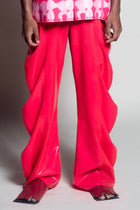 A pair of pink latex deflated trousers with a baggy fit, oversized style, and ankle gathering.