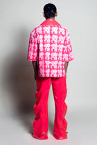 Person wearing a pink and white patterned shirt with bright pink pants on a white background