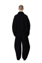 Person wearing a black textured outfit on a white background