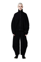 Person wearing a black textured outfit on a white background