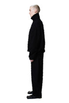 Person wearing a black textured outfit on a white background