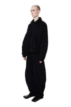 Person wearing a black textured outfit on a white background