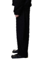 Black textured pants worn by a person on a white background