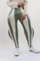 Person wearing a white jacket and green and white striped pants on a white background