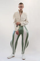 A model wearing white and olive striped inflatable trousers with a beige jacket, standing against a plain background.