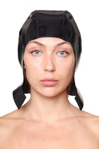 HARRI Black Cap with Ear Flaps made of shiny fabric worn by woman on white background