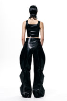 Back view of model wearing HARRI black cropped fitted tank top with shiny black wide-leg pants