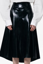 HARRI black pleated skirt with a shiny finish worn with a white blouse