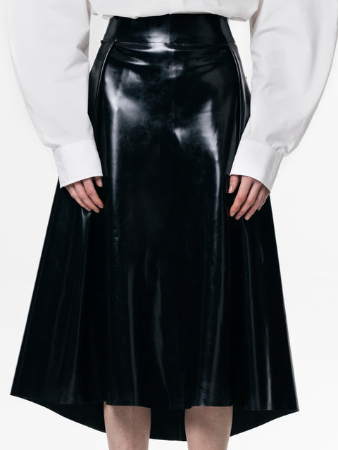 HARRI black pleated skirt with a shiny finish worn with a white blouse