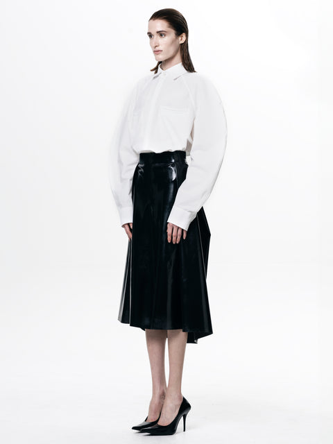 Woman wearing a HARRI black pleated skirt paired with a white long sleeve shirt and black heels