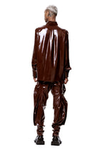 Back view of model wearing HARRI EXCLUSIVE Brown Alien Legs Inflatable Trousers in shiny material